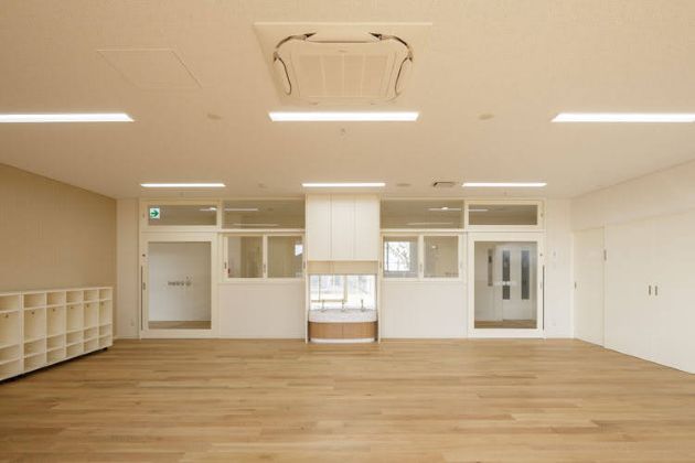 入口ドアも全面ガラスで開放的な幼児の保育室(写真は竣工時)。白い壁と木目の床があたたかい。